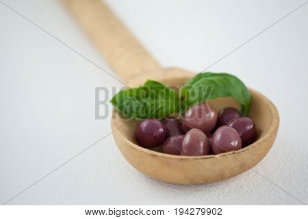 Close up of brown olives with herb in woden laddle on ladle