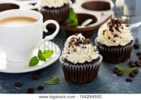 Chocolate cupcakes with vanilla frosting and a cup of coffee