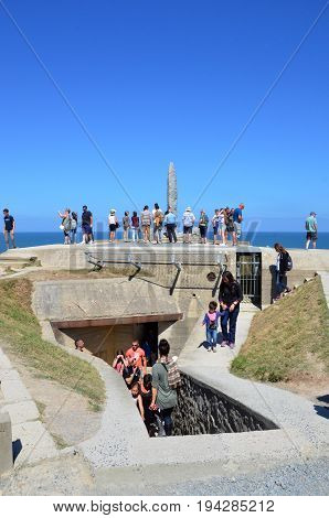 POINTE DU HOC FRANCE - AUG 12: Visitors look at the Ranger Monument at Pointe Du Hoc France on August 12 2016. The Monument sits atop a German observation bunker.
