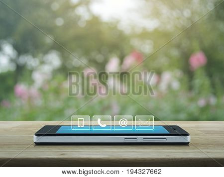Telephone mobile phone at and email buttons on modern smart phone screen on wooden table over blur pink flower and tree Customer support concept