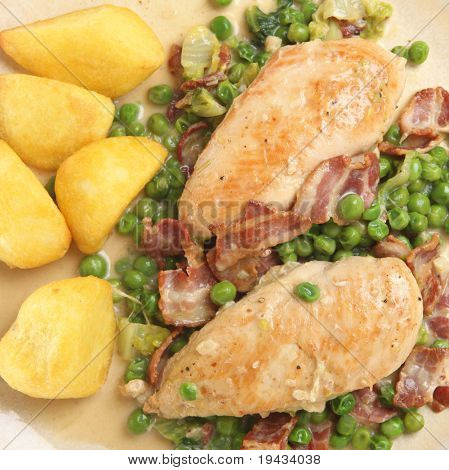Pollo francese con pancetta e piselli servito con patate arrosto.