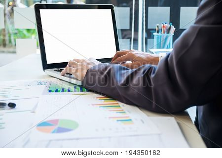 Business Man Using Laptop Computer On Office Table With Business Documents And Graph Financial With