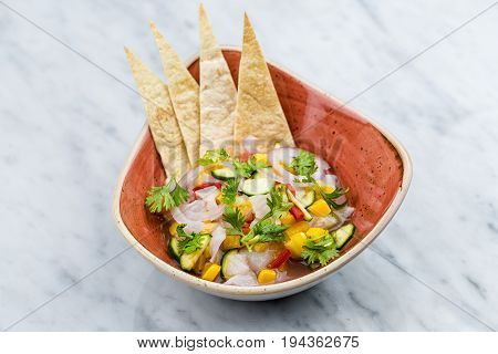 Fresh Mango Salsa with raw fish filet in brown plate on marbel desk
