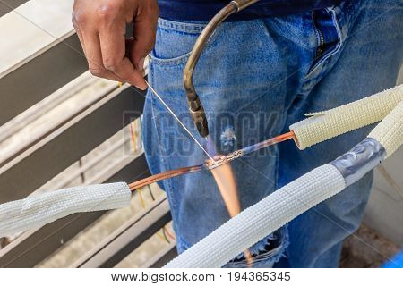 Hand of Worker welds copper tube oxyfuel gas welding repair air-condition