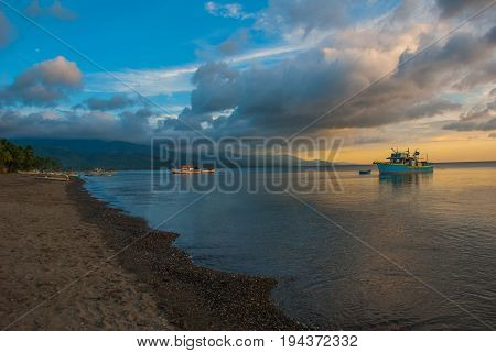 The Volcanic Sandy Beach At Sunset. The Ships At Sea. Pandan, Panay, Philippines.