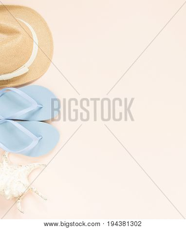 Summer fashion summer outfit on cream background. Blue flip flops seashell and straw hat. Flat lay top view