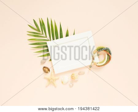 Empty frame and summer holidays items on creme background. Seashells and starfish. Selective focus. Place for text. Flat lay top view.