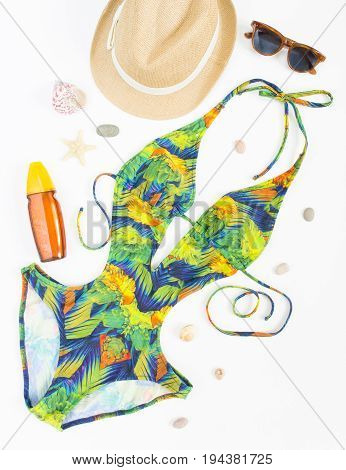 Summer outfit beach outfit summer stuff. Exotic pattern swimsuit retro sunglasses and straw hat. Flat lay top view.