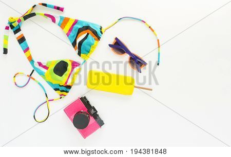 Summer background beach outfit girl summer stuff. Geometric abstract pattern swimsuit bright sunglasses pink retro camera and ice cream. Flat lay top view.