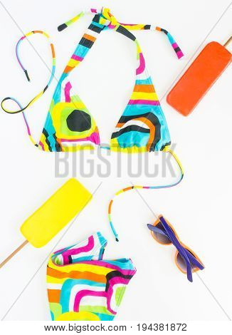 Summer background beach outfit girl summer stuff. Geometric abstract pattern swimsuit bright sunglasses and ice cream. Flat lay top view.