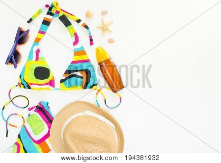 Summer background beach outfit girl summer stuff. Geometric abstract pattern swimsuit straw hat and sun protection spray. Flat lay top view.