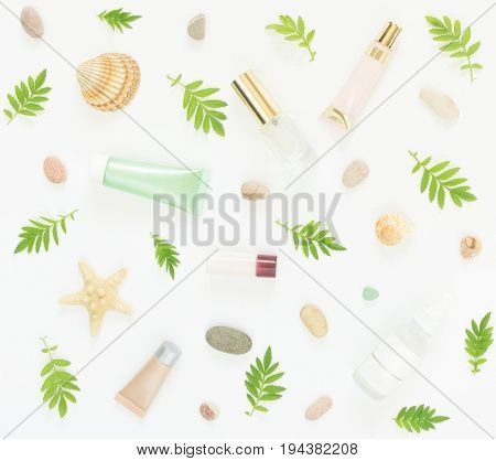 Cosmetics background. Cosmetics SPA makeup tubes, bottles, sea pebbles and shells on white background. Flat lay, top view.