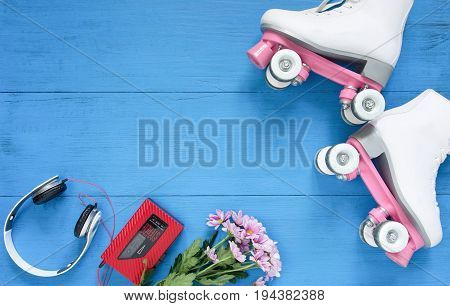 Sport, healthy lifestyle, roller skating background. White roller skates, headphones and vintage tape player. Flat lay, top view.