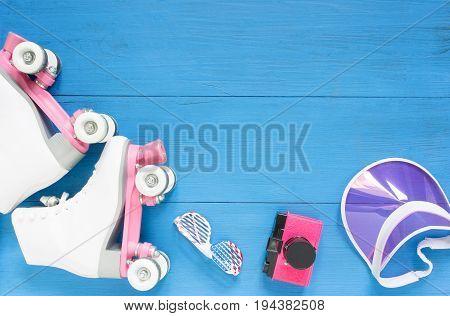 Sport, healthy lifestyle, roller skating background. White roller skates, sunglasses, pink visor hat and vintage camera. Flat lay, top view.