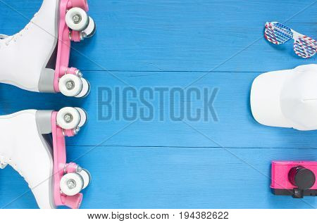 Sport, healthy lifestyle, roller skating background. White roller skates, sunglasses, white baseball cap, vintage pink camera. Flat lay, top view.