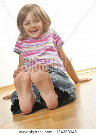 smilling little girl sitting on a wooden floor