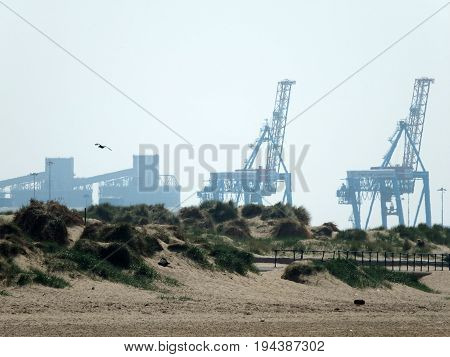 crosby beach in mersyside with large dockside cranes and sand dunes
