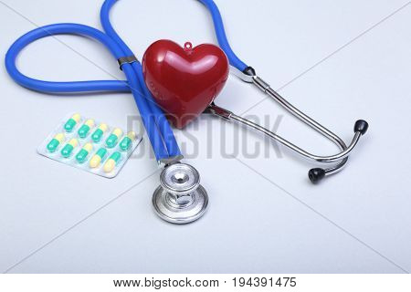 RX prescription, Red heart, asorted pils and a stethoscope on white background.
