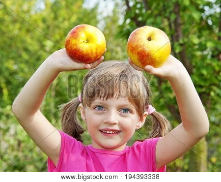 little girl with two apples in the garden