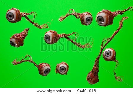Torn out eyeball flying around isolated over green