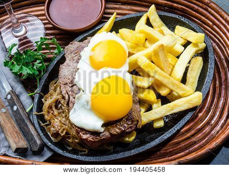 Peruvian Latin American food. Lomo a lo pobre. Beef whit fried potatoes french fry and egg served with chile sauce and wine