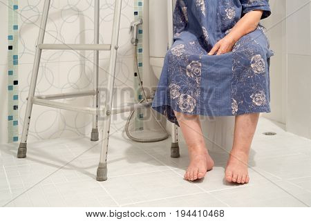 Senior women using the toilet with walker .