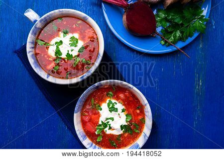 Ukrainian Traditional Borsch. Russian Vegetarian Red Soup  In Blue Bowl On Blue Wooden Background.