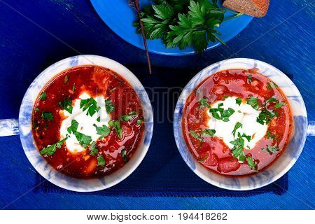 Ukrainian Traditional Borsch. Russian Vegetarian Red Soup  In Blue Bowl On Blue Wooden Background.