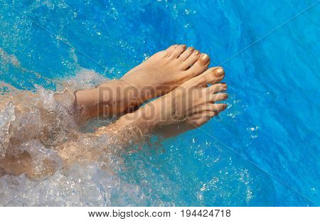 Bare Feet Of Woman On The Pool Water