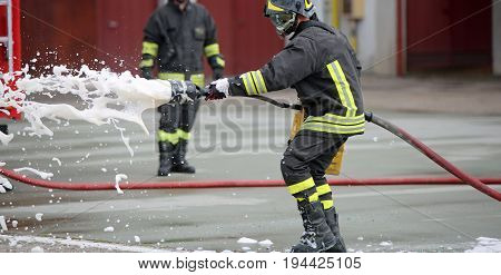 Firefighters while extinguishing the fire with a special fire extinguishing equipment with foma