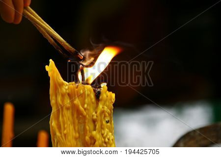 A lighted candle and lit incense with candles frame on the altar of Buddha at temple. a cultural offering for temple prayers.