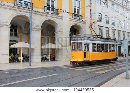 LISBON, PORTUGAL - JUNE 7, 2017: Lisbon yellow tram on the way to Commerce Square in old town Lisbon, Portugal. Famous typical tourist travel attraction on sunny summer day. Colorful architecture city buildings street background view