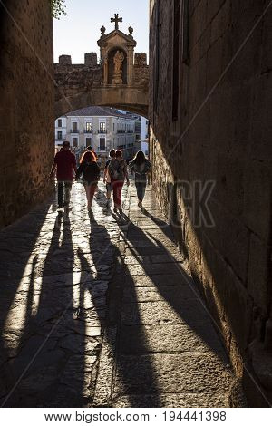 Caceres Spain - July 1 2017: Tourists walking under Star Arch or Arco de la Estrella Caceres. Sunset light
