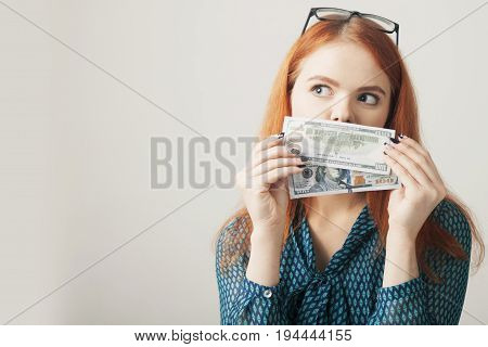 Business Woman covering her mouth with a dollar banknote as symbol of as a symbol of bribery cheating financia and l political manipulation.