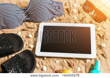 Summer bikini and accessories stylish beach set, Beach bikini summer outfit and sea sand as background, Top View, Concept. Copy space. Sun flare