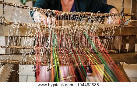 Craftsperson Woman working behind an old wooden loom in workshop