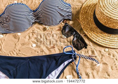 Summer bikini and accessories stylish beach set, Beach bikini summer outfit and sea sand as background, Top View, Concept. Copy space