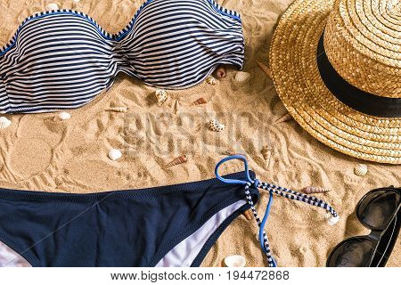 Summer bikini and accessories stylish beach set, Beach bikini summer outfit and sea sand as background, Top View, Concept. Copy space