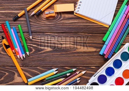 Back to school. Different stationery - pencils pen note erazer paint on wooden background. Top view. Place for text.