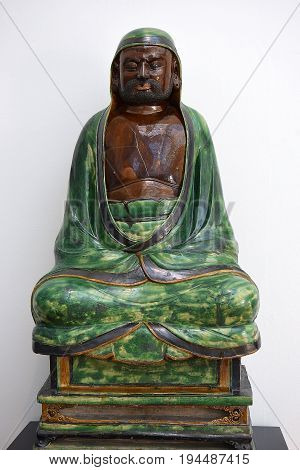 LONDON, ENGLAND - May 24,2017: sculpture (stoneware with green and brown glazes) seated Bodhidharma, ming dynasty, was buddhist monk, first chinese patriarch, Victoria and Albert Museum, London, UK