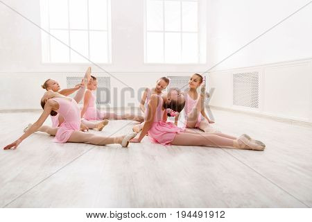 Little girls dancing ballet in studio. Young ballerinas stretching before performance, classical dance school
