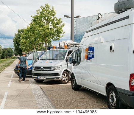 STRASBOURG FRANCE - JUN 30 2017: Engineer walking near TV Media Television Trucks with multiple Satellite parabolic antennas and fiber optic cables preparing to report live the official European Ceremony of Honor for Dr. Helmut Kohl at European Parliament