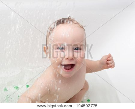 Picture of the laughing little baby playing in the bathtub