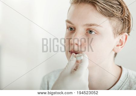 Doctor Taking Temperature Of Young Teenage Boy