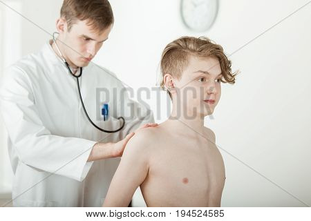 Doctor Examining Back Muscles Of Teen Boy