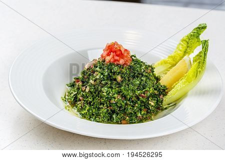 Arabic traditional salad Tabbouleh with Fresh Parsley, Tomatoes, Cracked Wheat, Onions, Freshly Squeezed Lemon Juice Virgin Olive Oil.