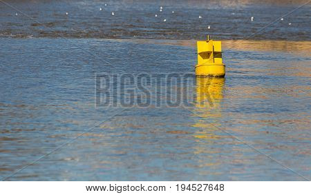 Yellow iron buoy floats in the blue water the river shows the level of the ships to the ships for a safe walk