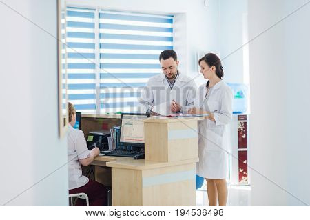 Busy reception in a hospital with doctors and receptionists.