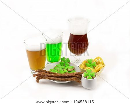 Light camp green and dark beer in a glass with appetizers on a table with clovers on a white background. The day of St. patrick