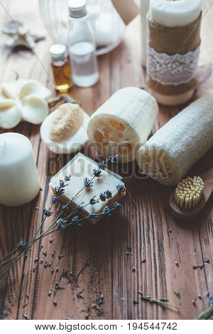 Natural spa products and decor for bath. Handmade herbal soap, organic oil, lavender, loofah and beauty products on wooden desk, closeup photo.
